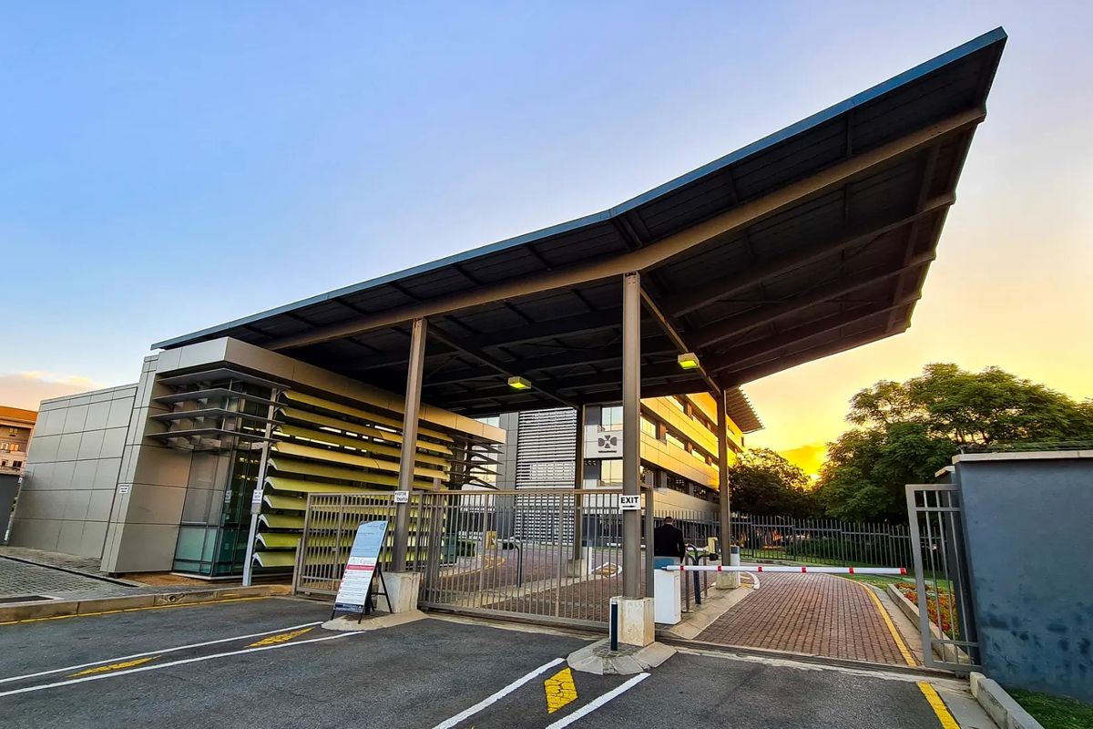 Commercial property entrance featuring a modern metal canopy, security boom gate, and louvred facade elements, providing a professional and secure access point.