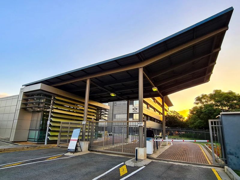 Commercial property entrance featuring a modern metal canopy, security boom gate, and louvred facade elements, providing a professional and secure access point.