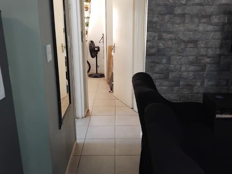 A tiled hallway featuring a stone veneer accent wall, providing a transition between living areas and secondary rooms.