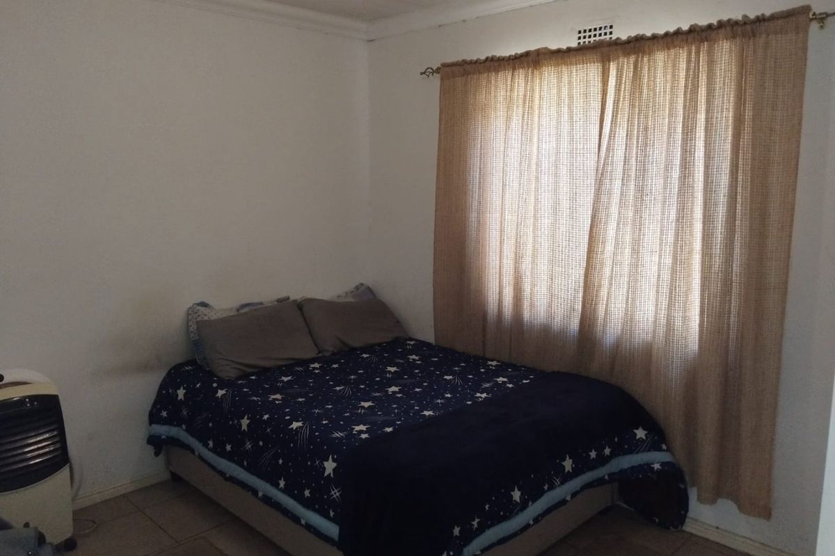 A bedroom featuring tiled flooring and a ceiling vent, currently requiring cosmetic updates to the wall finishes.