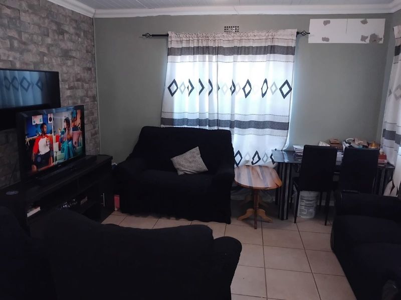 A living room featuring a stone veneer accent wall and tiled flooring, requiring minor wall repairs.