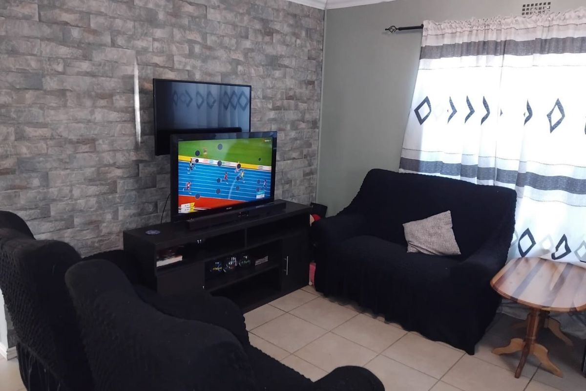 A living room featuring tiled flooring and a textured stone-look feature wall, providing a neutral base for interior design updates.