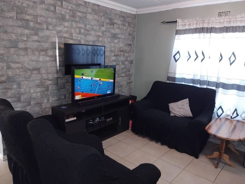 A living room featuring tiled flooring and a textured stone-look feature wall, providing a neutral base for interior design updates.