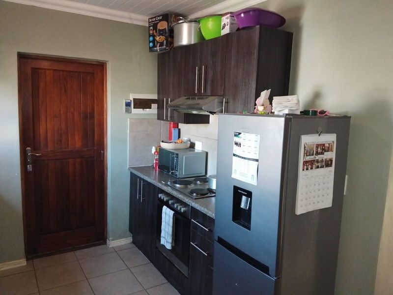 A functional kitchen featuring dark wood cabinetry, built-in oven with hob, extractor fan, and tiled flooring, providing a practical workspace.