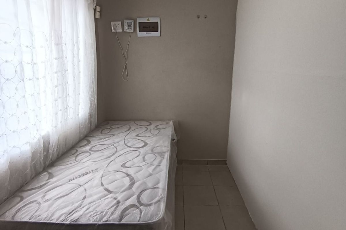 A compact bedroom featuring tiled flooring and a wall-mounted electrical distribution board.