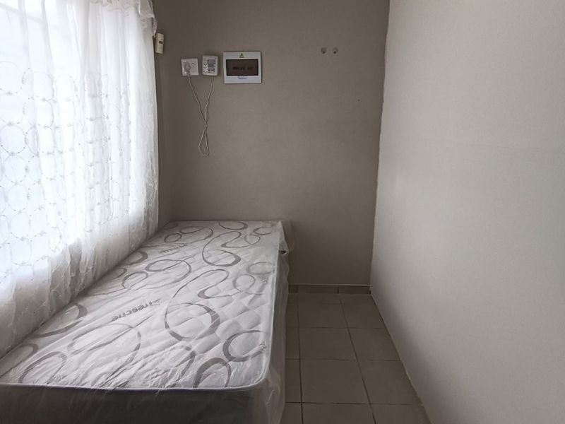 A compact bedroom featuring tiled flooring and a wall-mounted electrical distribution board.