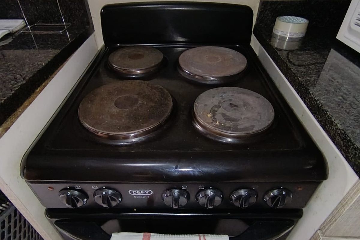 A close-up view of a freestanding electric stove set between granite countertops in a kitchen.