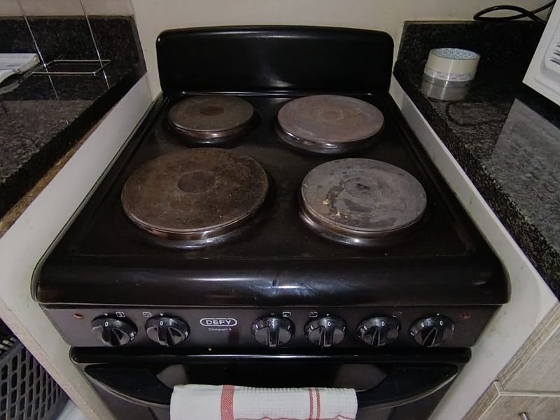A close-up view of a freestanding electric stove set between granite countertops in a kitchen.