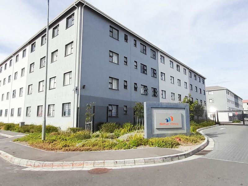 Exterior view of the Belhar Views residential complex, featuring multi-story apartment blocks, paved driveway access, and landscaped garden areas.