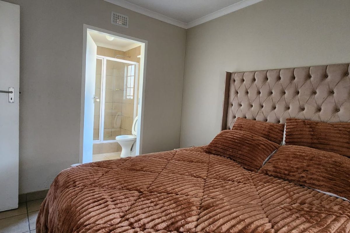 A well-maintained bedroom featuring tiled flooring, built-in cupboards, and direct access to an en-suite bathroom.