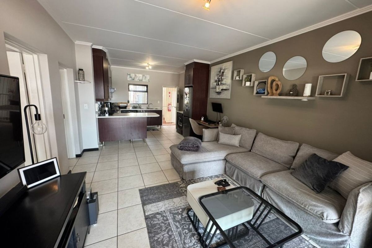 Open plan living area featuring tiled floors and a functional kitchen with built-in cabinetry and a peninsula, creating a cohesive living and dining space.