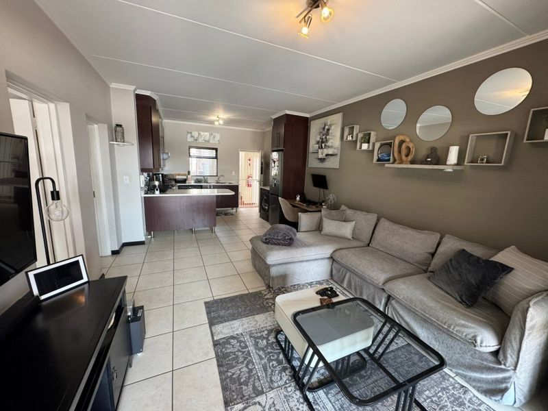 Open plan living area featuring tiled floors and a functional kitchen with built-in cabinetry and a peninsula, creating a cohesive living and dining space.