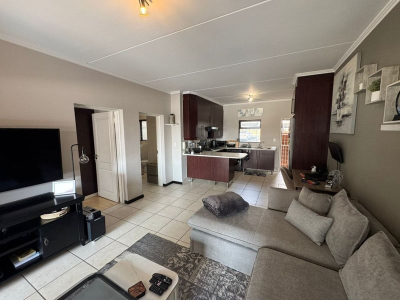 Open-plan living area featuring a kitchen with dark wood cabinetry, tiled flooring, and direct access to adjacent rooms.
