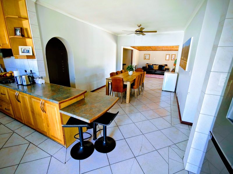 Open plan kitchen and dining area featuring tiled flooring, wooden cabinetry, and a ceiling fan, creating a functional and connected living space.