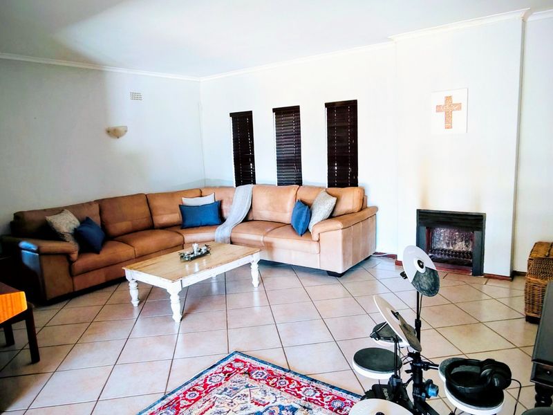 Spacious living room featuring tiled flooring, a built-in fireplace, and dark venetian blinds, offering a comfortable and functional family space.