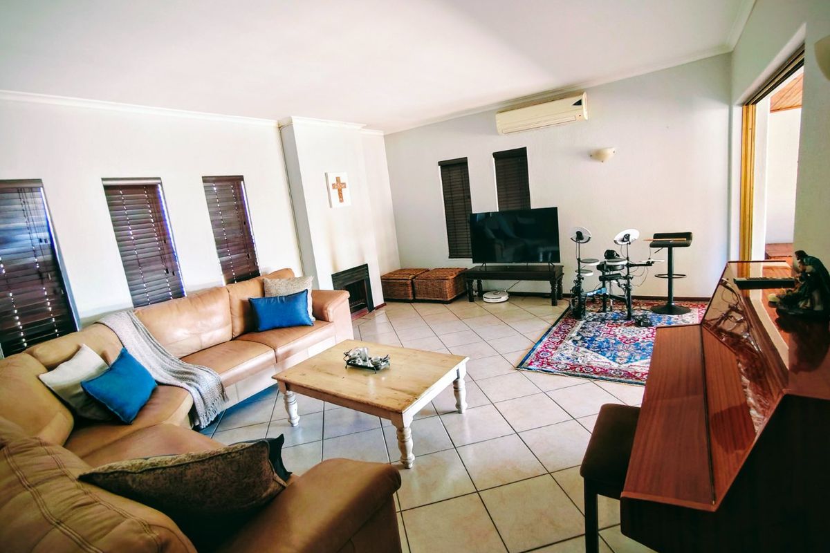 Spacious living room featuring tiled flooring, a built-in fireplace, and a wall-mounted air conditioning unit, offering a comfortable and functional family space.