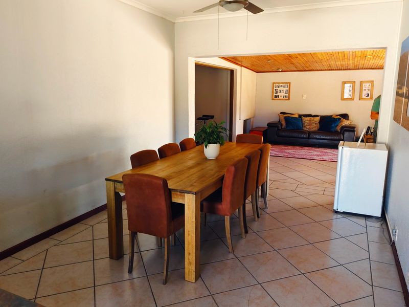 Open-plan dining and living area featuring tiled flooring, a ceiling fan, and a distinct timber-paneled ceiling in the lounge section.