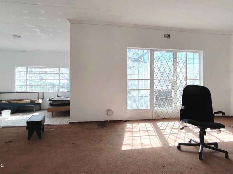 Spacious living area featuring a brick fireplace, security gates, and dual flooring finishes, offering a blank canvas for renovation and modernization.