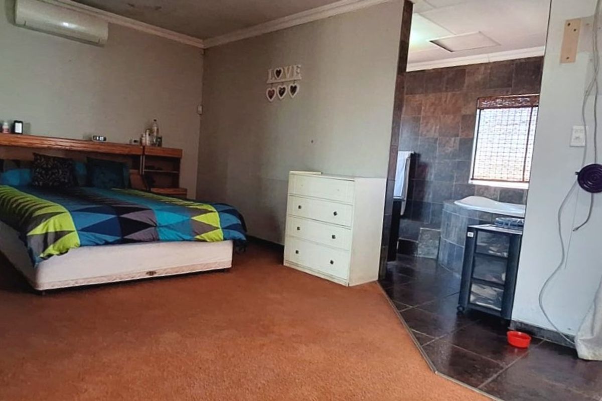 Spacious bedroom featuring an open-plan en-suite bathroom with a built-in bathtub, split-system air conditioning, and direct access to an outdoor area via a security gate.