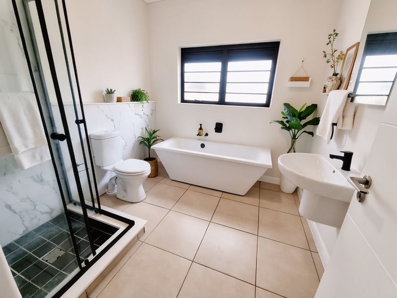 Modern bathroom featuring a freestanding bathtub, walk-in shower with black frame, wall-mounted basin, and elegant marble-look wall tiling with neutral floor tiles.