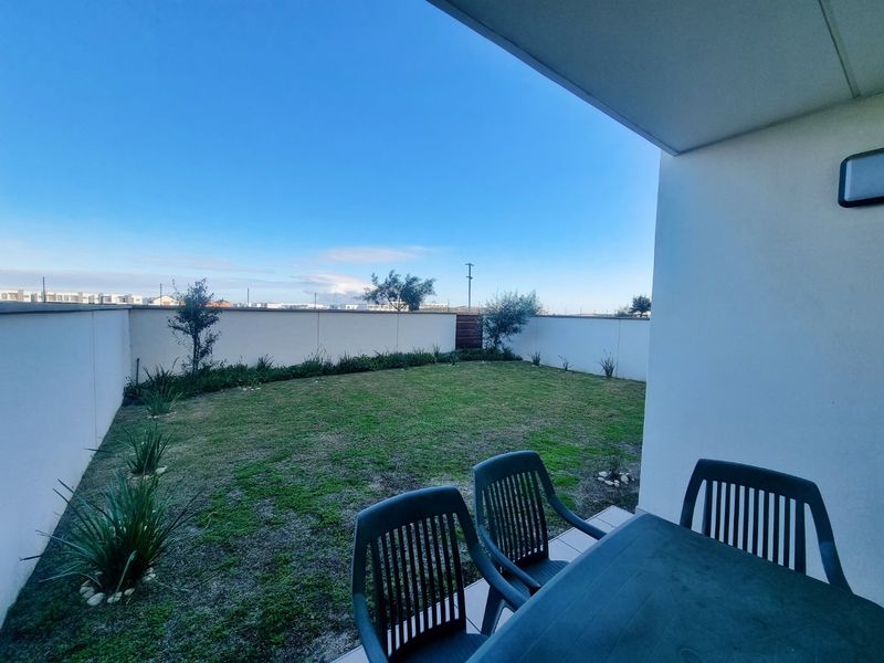 A covered patio area overlooking a private garden with high boundary walls, providing a secure and pleasant outdoor space.