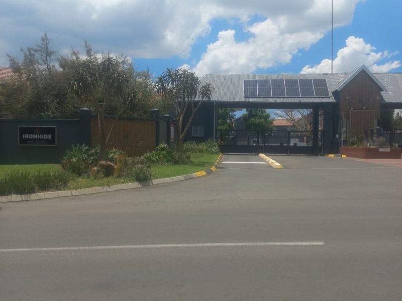 The entrance to Ironhide complex featuring a secure gated access point, solar panels, and landscaped boundary walls.