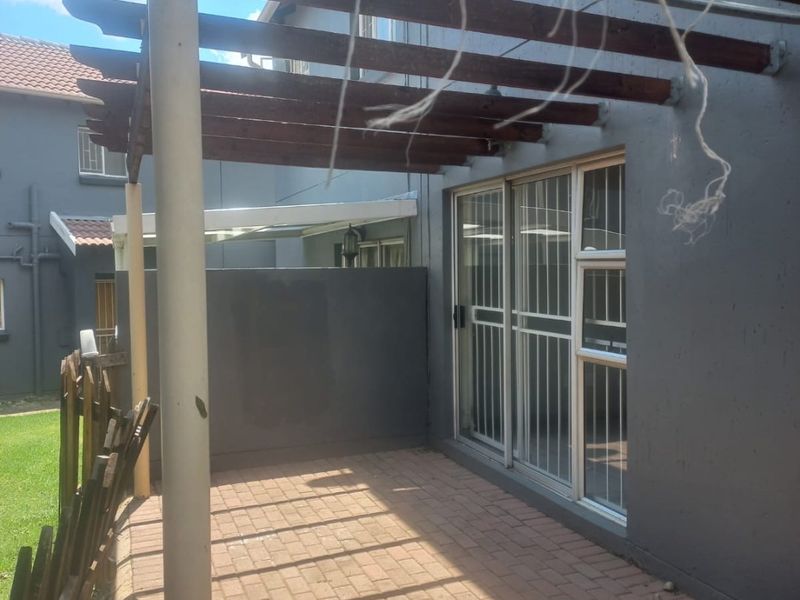 A paved outdoor patio area featuring a timber pergola, providing a functional space for outdoor relaxation adjacent to the main living area.