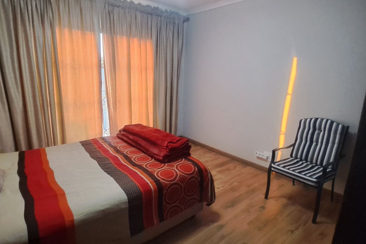 A bedroom featuring laminate flooring and a sliding door with curtain tracks, providing access to the exterior.