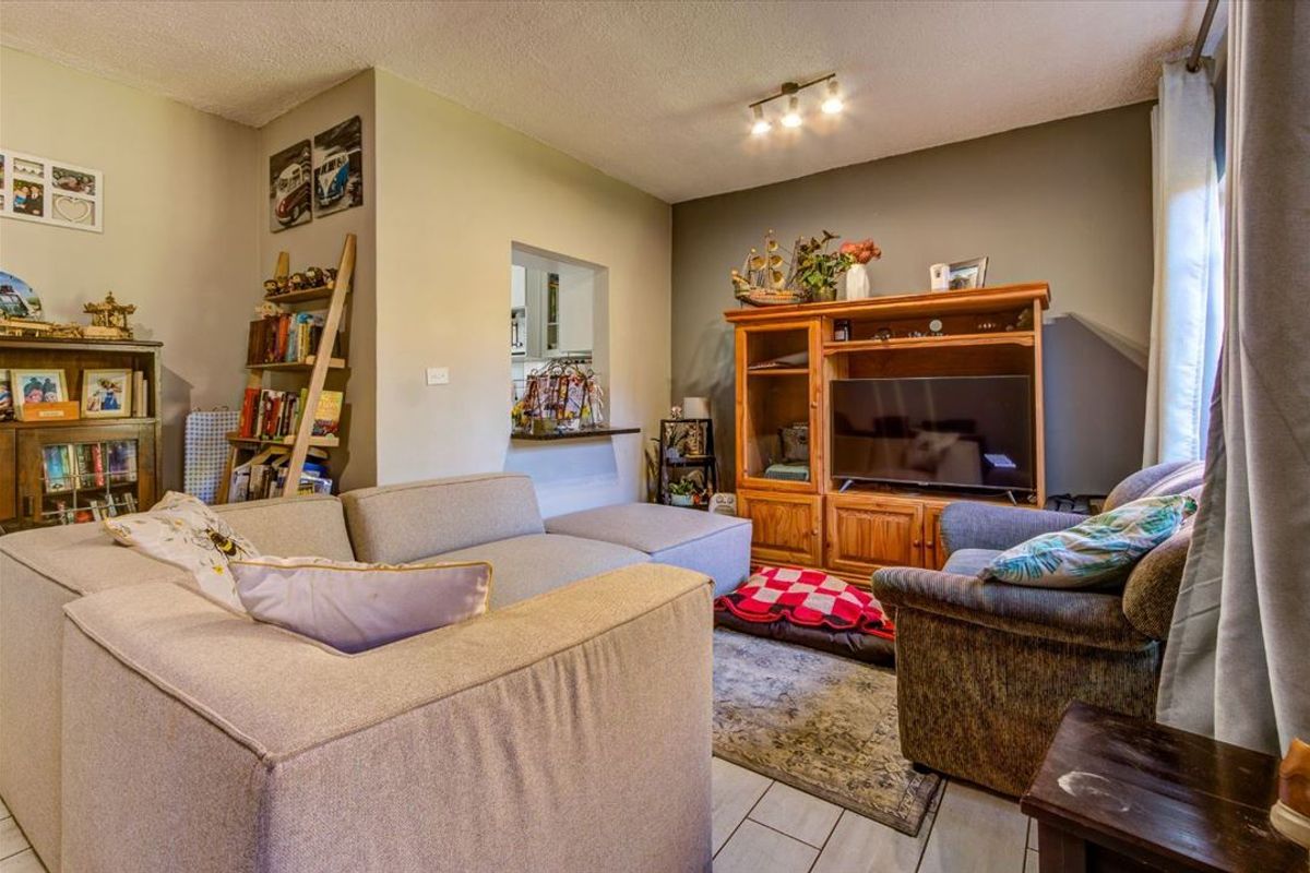 A comfortable living room featuring tiled flooring and a convenient pass-through window connecting to the kitchen area.