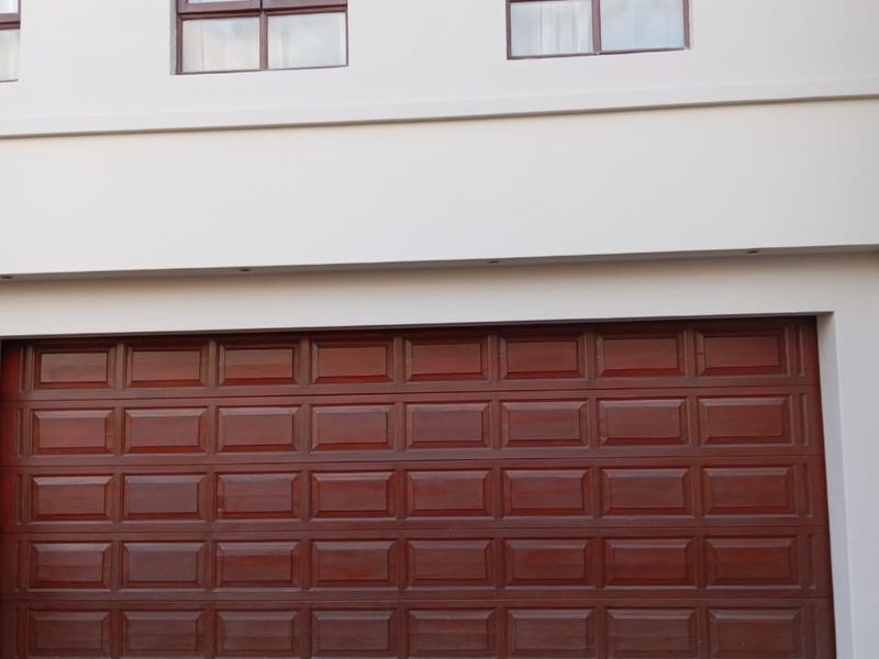 Front elevation of the property featuring a double garage door with a paved driveway and upper-level windows.
