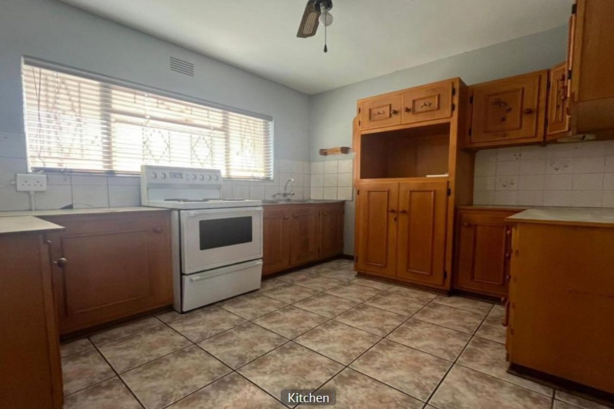 A functional kitchen featuring wooden cabinetry, tiled flooring, and a tiled backsplash, offering a blank canvas for potential modern updates and renovation.