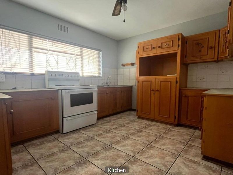 A functional kitchen featuring wooden cabinetry, tiled flooring, and a tiled backsplash, offering a blank canvas for potential modern updates and renovation.