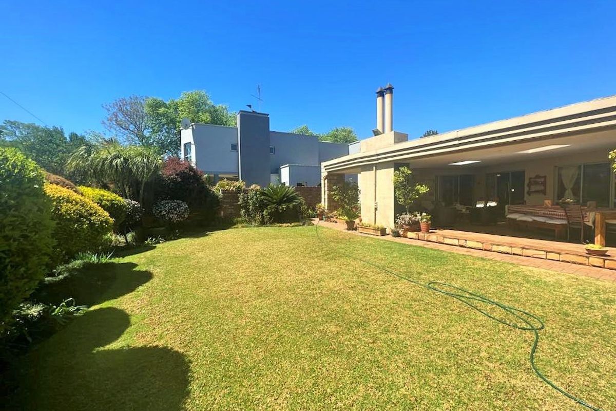A well-maintained rear garden featuring a spacious covered patio, brick paving, and a built-in chimney, perfect for outdoor living and entertaining.