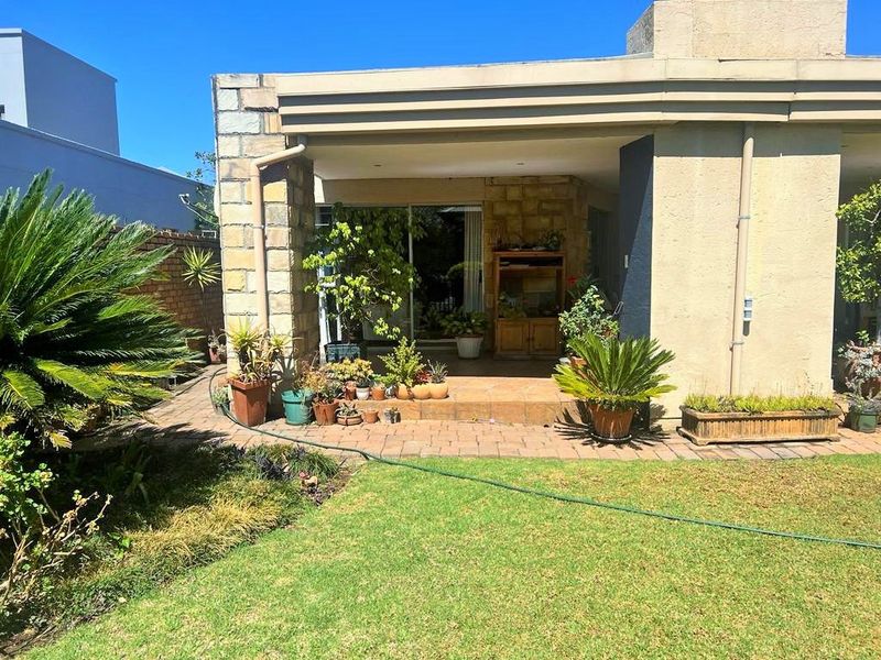 A covered patio area featuring stone cladding and tiled flooring, providing a seamless transition from the interior living space to the rear garden.