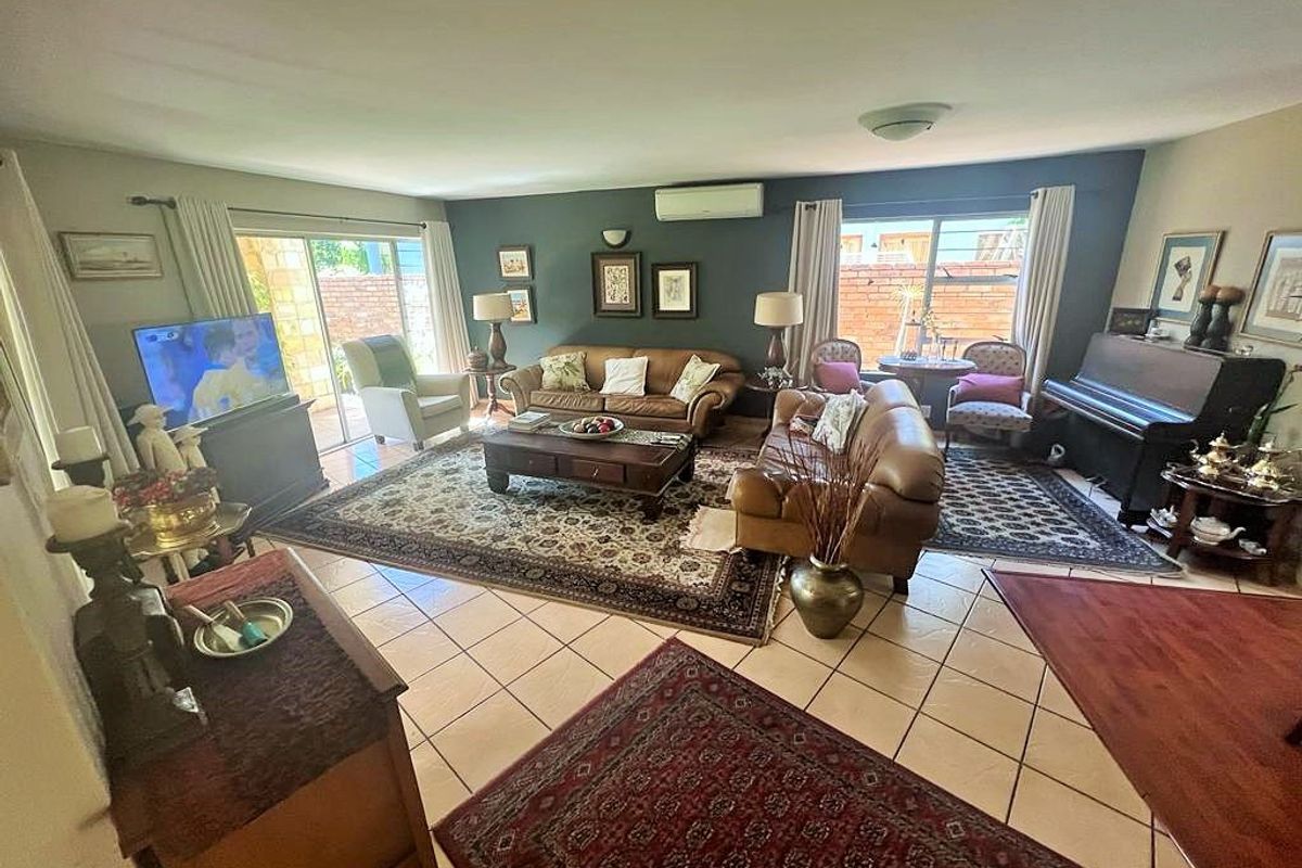 Spacious living room featuring ceramic floor tiles, split-system air conditioning, and large sliding glass doors providing access to the outdoor area.