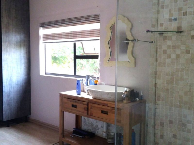 Bathroom featuring a vessel sink on a wooden vanity, glass-enclosed shower with mosaic tiling, and a built-in wardrobe.