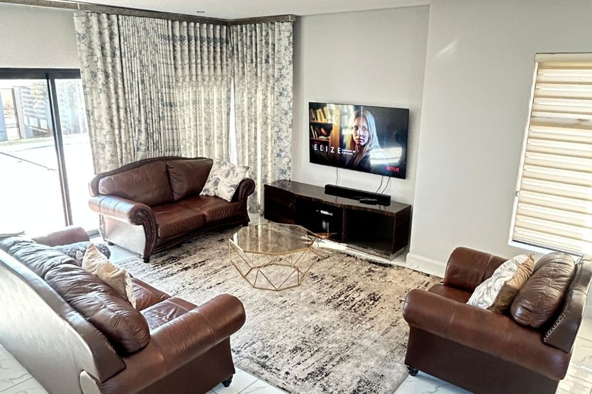 A bright and spacious living room featuring large format marble-look floor tiles, recessed downlights, and sliding glass doors leading to the exterior.