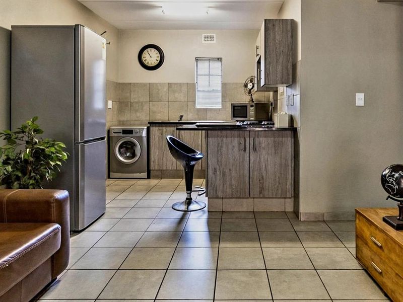 Open-plan living area featuring a functional kitchen with built-in cabinetry, tiled flooring, and a tiled backsplash, seamlessly integrated with the living space.