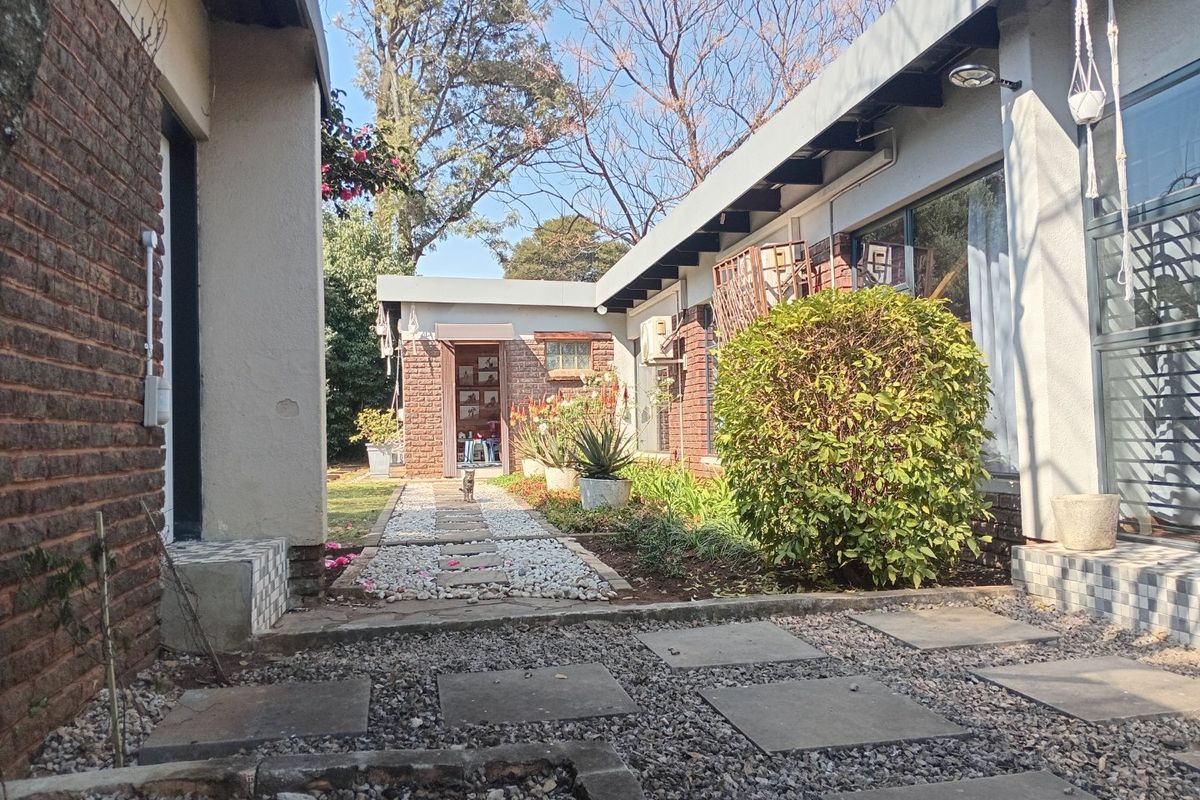 A rear courtyard area featuring a gravel path, paved stepping stones, and brick-walled building elevations with large glass sliding doors.