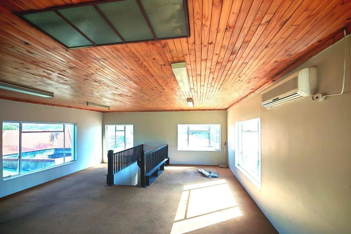 Spacious, empty upper-level living area featuring a timber tongue and groove ceiling, split-system air conditioning, and a staircase with a wooden balustrade.