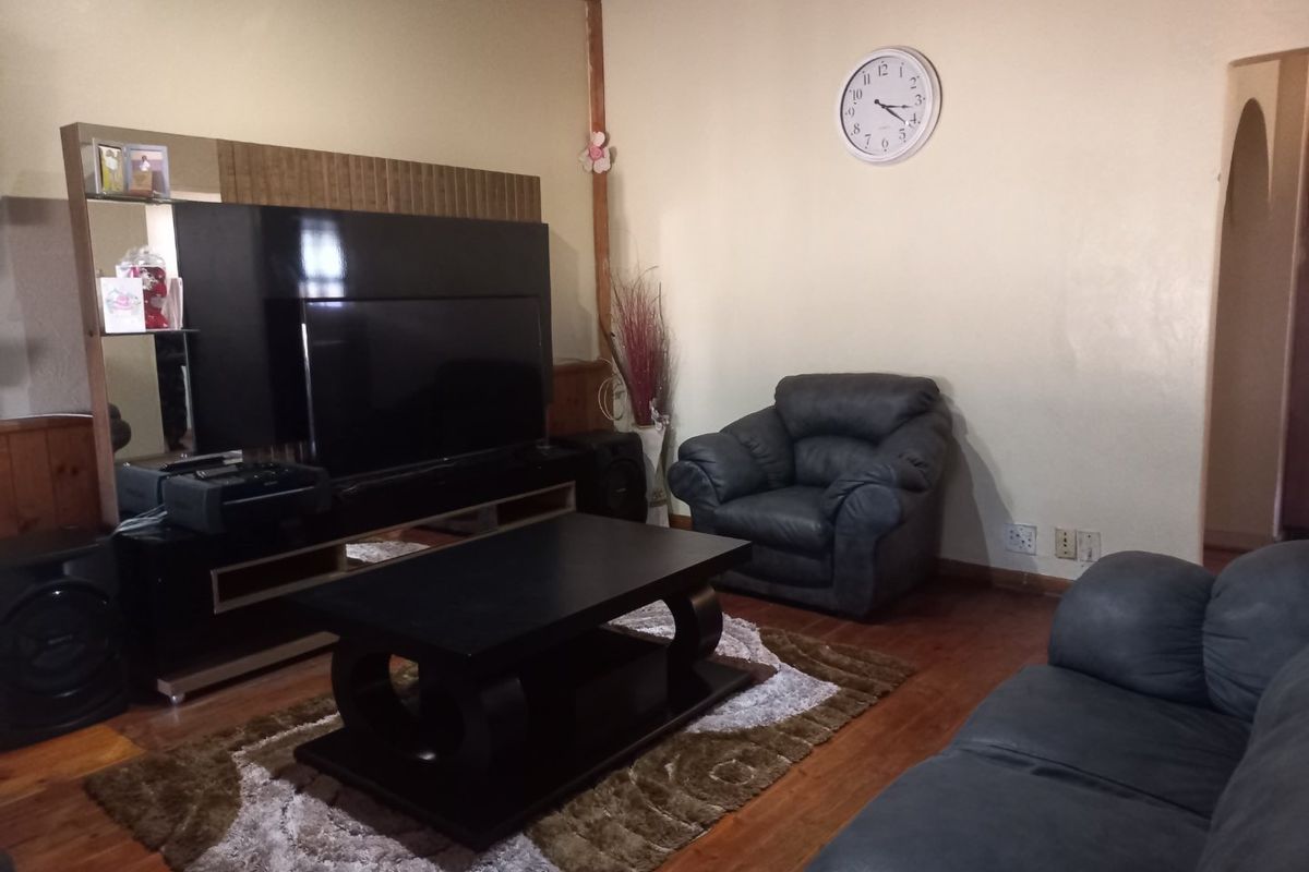 A living room featuring timber flooring and a timber ceiling, with an archway leading to an adjacent space.