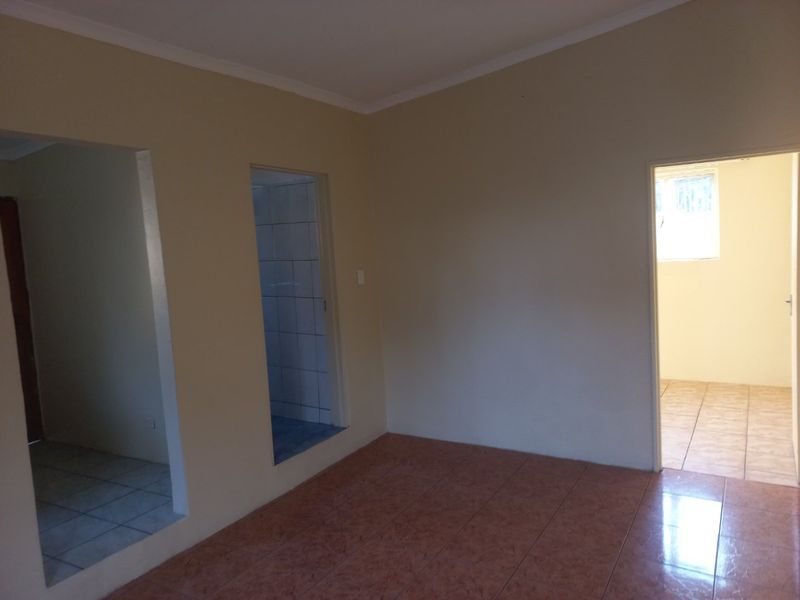 An empty living area featuring tiled flooring and neutral wall finishes, providing a blank canvas for interior design and furniture placement.