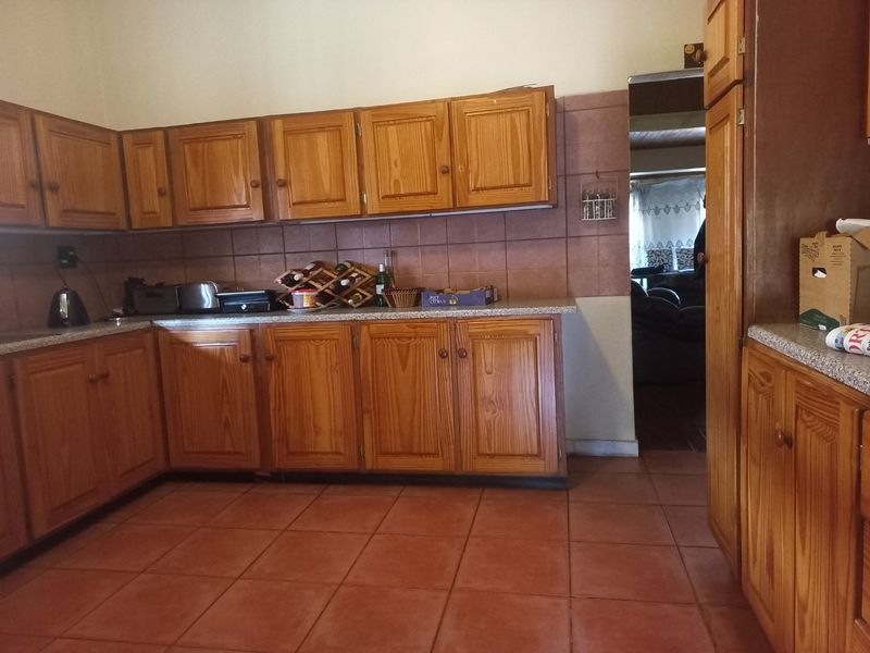 A functional kitchen featuring traditional wooden cabinetry, tiled backsplash, and durable floor tiles, offering a classic layout with ample storage space.