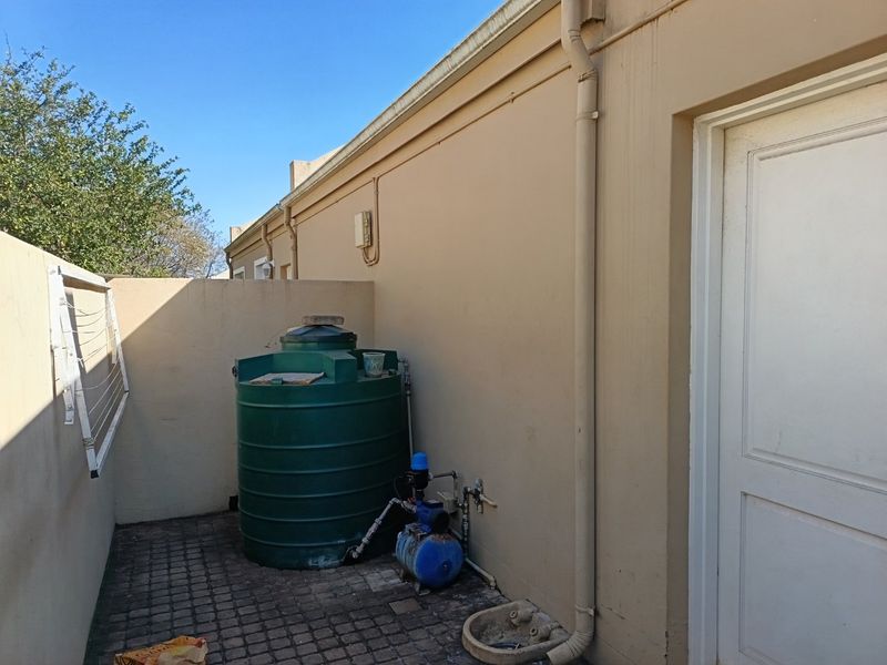 A utility area featuring a water storage tank and pump system, situated against the exterior wall of the townhouse.