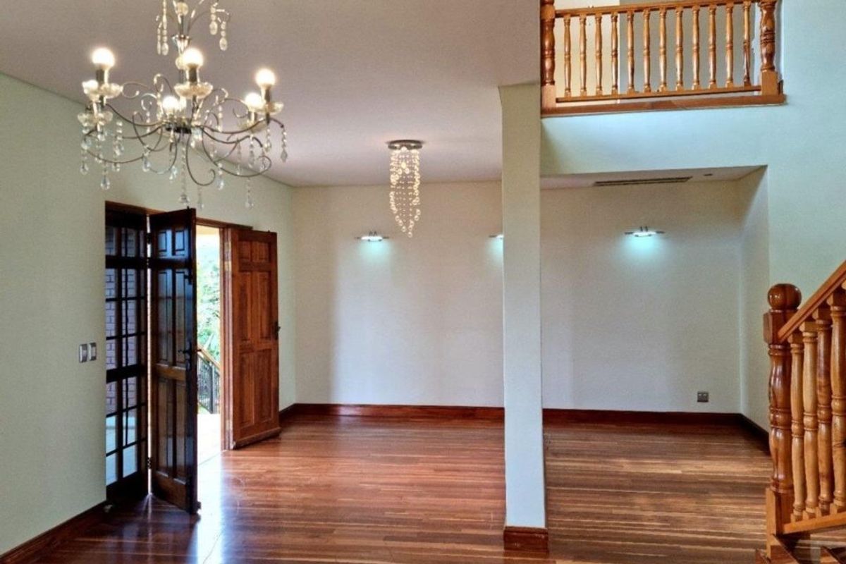 Spacious open-plan living area featuring polished hardwood floors, a grand wooden staircase, and a mezzanine landing with elegant crystal chandeliers.