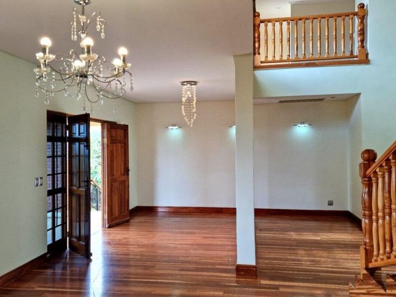 Spacious open-plan living area featuring polished hardwood floors, a grand wooden staircase, and a mezzanine landing with elegant crystal chandeliers.
