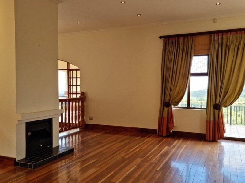 Spacious living room featuring polished hardwood flooring, a built-in fireplace, and access to an adjoining balcony through an elegant archway.