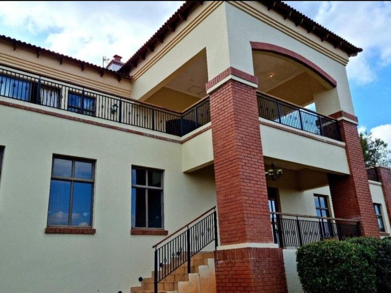 A multi-story residential exterior featuring brick pillar accents, wrought iron balcony railings, and a covered upper-level terrace.