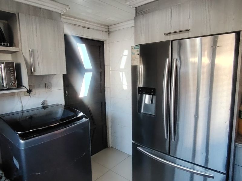 A functional laundry area featuring built-in cabinetry, tiled flooring, and direct access to the exterior.