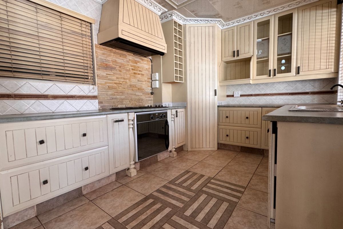 A functional kitchen featuring built-in cabinetry, a stone tile backsplash, integrated oven, and ceramic floor tiles, offering a classic layout ready for modernization.